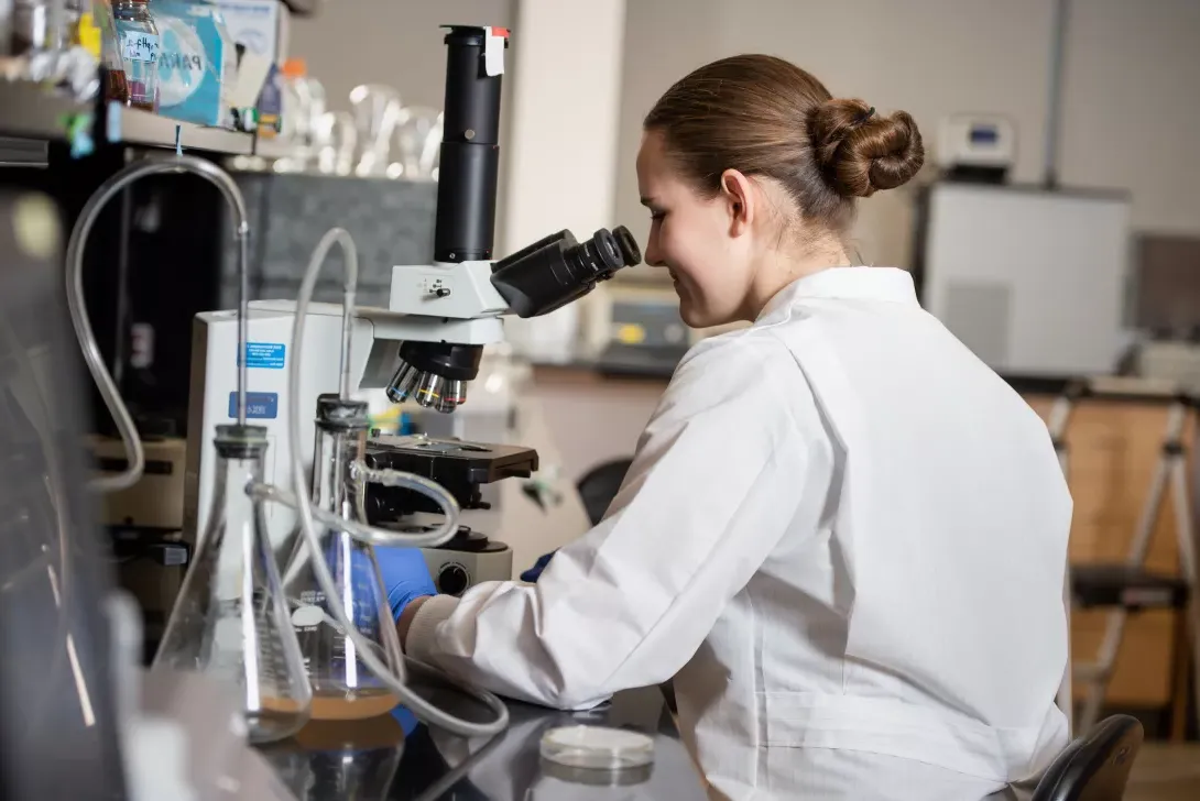 Student in microbiology lab using microscope